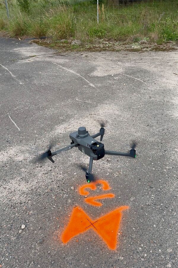 DJI-Drohne mit RTK-Modul startet über einem orange markierten Passpunkt für die lagegenaue Drohnenvermessung